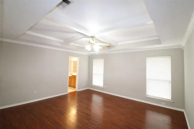 an empty room with wooden floor chandelier fan and windows