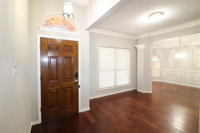 an empty room with wooden floor cabinet and windows
