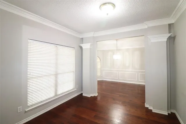 an empty room with wooden floor and windows with curtains