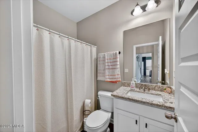 a bathroom with a granite countertop sink toilet and mirror