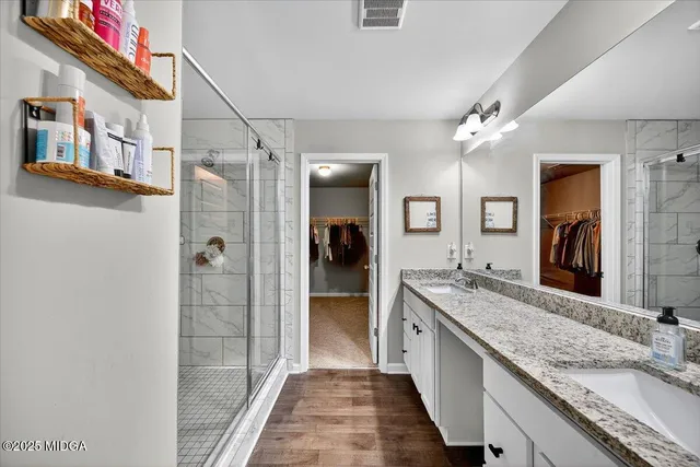a bathroom with a granite countertop double vanity and a shower