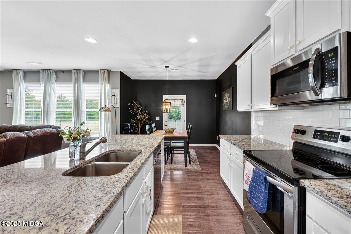 656 Dolly Drive Forsyth, GA 31029 - Photo 6 of 30 a kitchen with stainless steel appliances granite countertop a sink a stove and a wooden cabinets