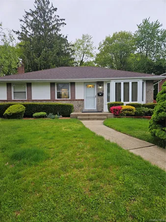 a front view of a house with a garden and trees