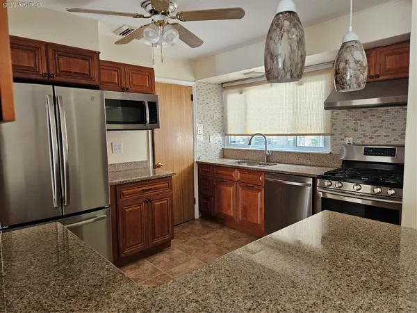 a kitchen with stainless steel appliances granite countertop a stove a sink and a refrigerator