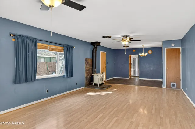 a view of an empty room with window and wooden floor