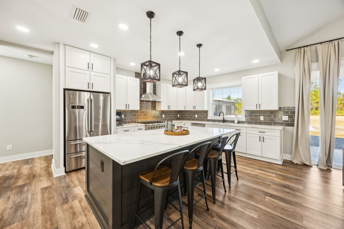 32500 Crossfire Trail Callahan, FL 32011 - Photo 18 of 64 a kitchen with stainless steel appliances kitchen island granite countertop a refrigerator a stove a sink a dining table and chairs with wooden floor