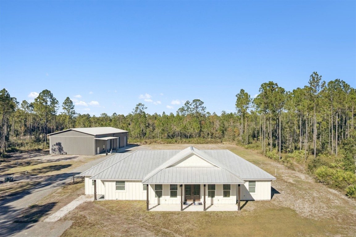 32500 Crossfire Trail Callahan, FL 32011 - Photo 2 of 64 a view of a white house with a yard and table and chairs under an umbrella