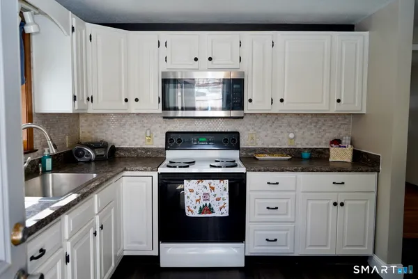 a kitchen with stainless steel appliances granite countertop a stove a sink and a white cabinets