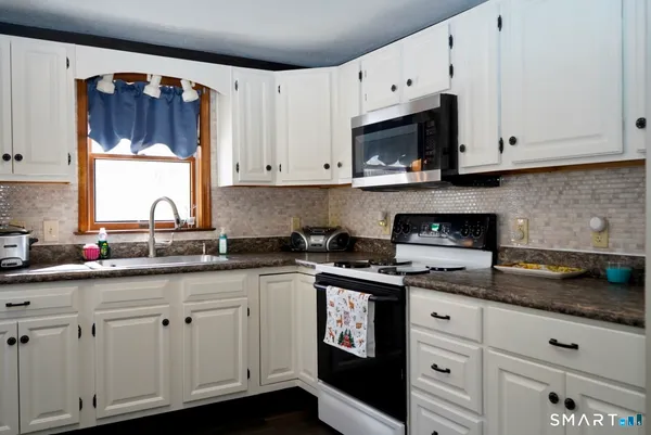 a kitchen with granite countertop white cabinets and a stove