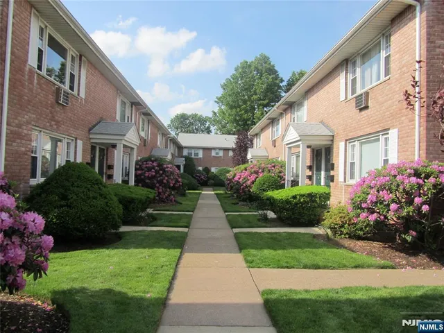 a front view of house and yard with beautiful flowers and green space