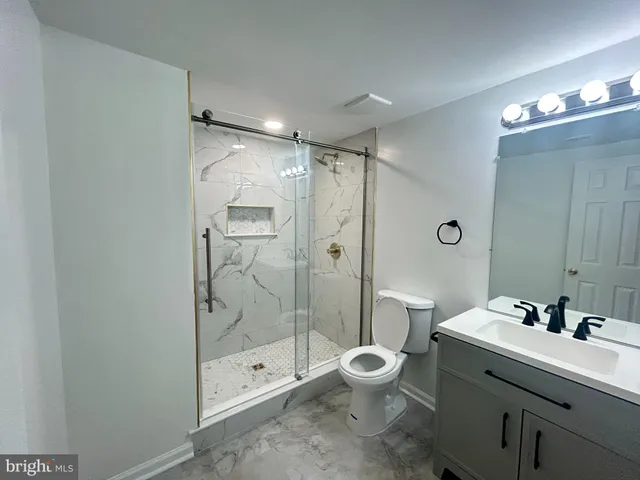 a bathroom with a shower sink mirror and toilet