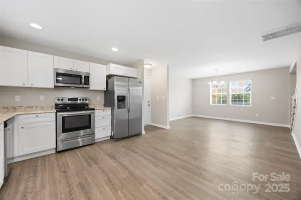 a kitchen with granite countertop a refrigerator and a stove top oven