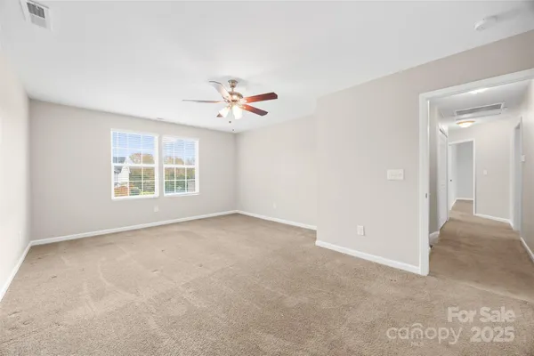 an empty room with windows and ceiling fan view
