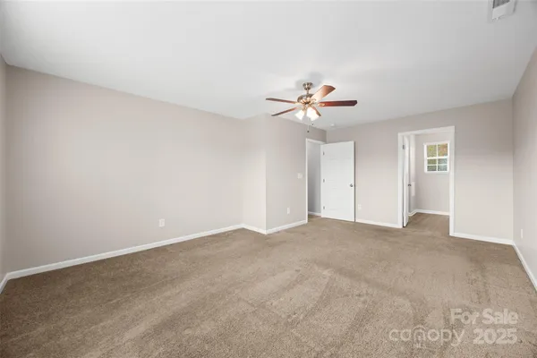a view of an empty room with a chandelier fan