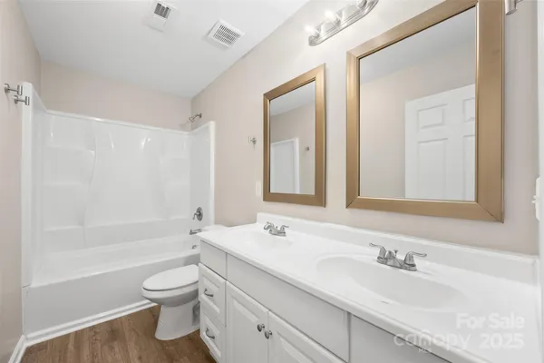 a bathroom with a bathtub shower sink vanity mirror and toilet