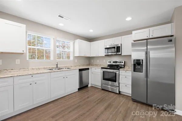 a kitchen with granite countertop white cabinets and stainless steel appliances