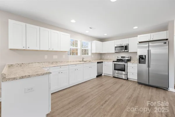 a kitchen with granite countertop white cabinets and stainless steel appliances