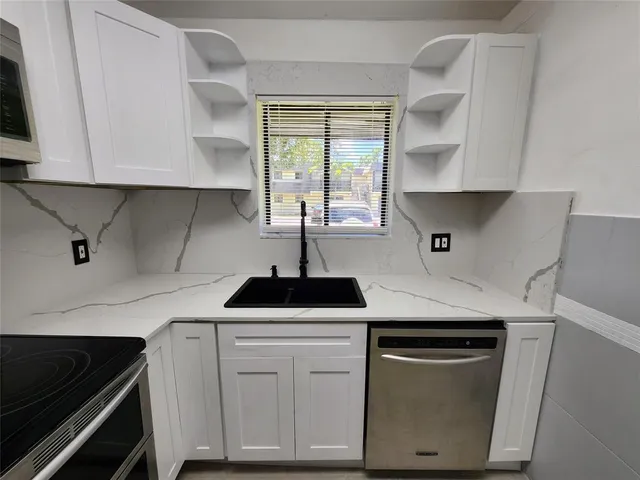 a kitchen with cabinets appliances a sink and a window