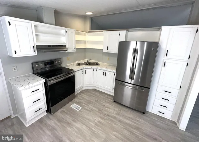 a kitchen with granite countertop a refrigerator stove and wooden floor