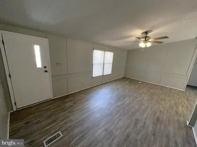 an empty room with wooden floor and a ceiling fan