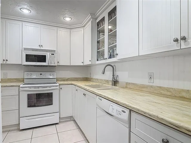 a kitchen with granite countertop white cabinets and white stainless steel appliances