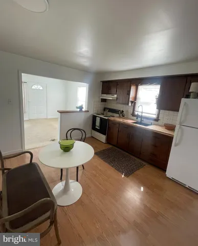 a kitchen with stainless steel appliances kitchen island granite countertop a sink a stove a microwave a dining table and chairs with wooden floor