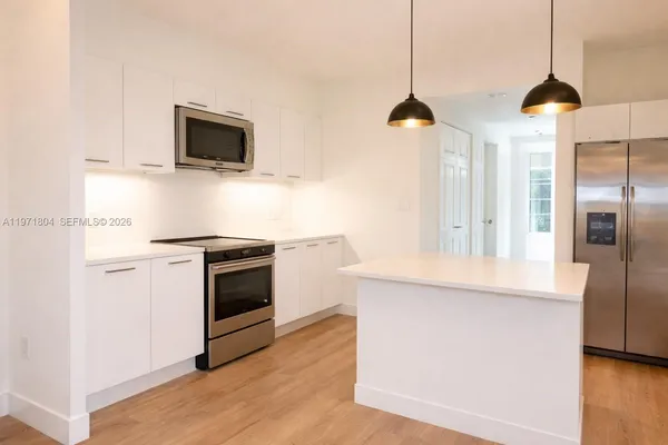 a kitchen with stainless steel appliances and wooden floor