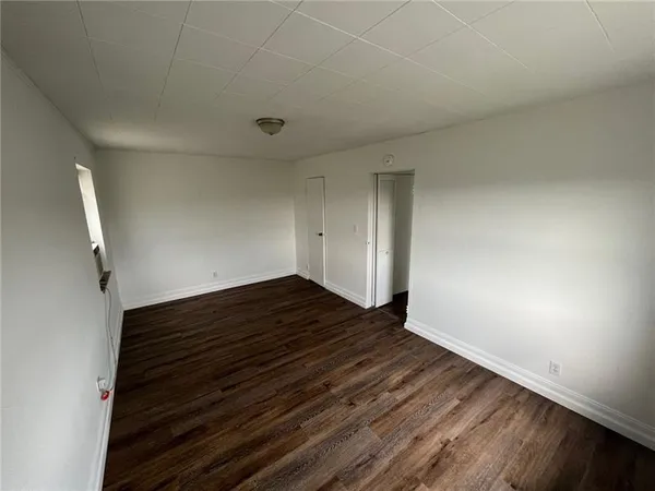 an empty room with wooden floor cabinet and windows