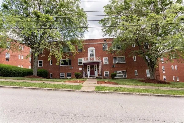 a view of a brick house with a big yard and large trees