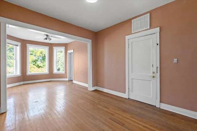 a view of an empty room with wooden floor and a window