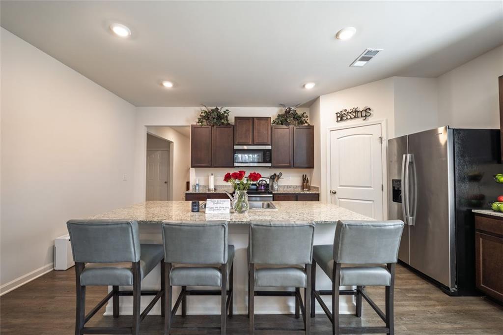 3841 Makeover Court Atlanta, GA 30349 - Photo 9 of 44 a kitchen with a dining table chairs refrigerator and microwave
