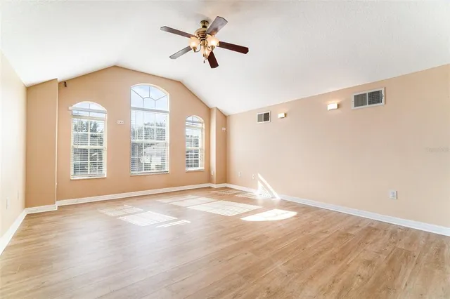 a view of an empty room with a window and wooden floor
