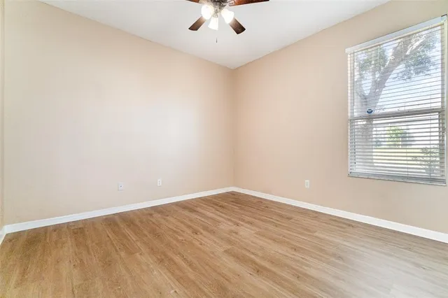 an empty room with a window and a ceiling fan