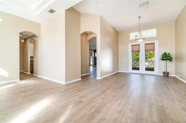 a view of an empty room with window and wooden floor