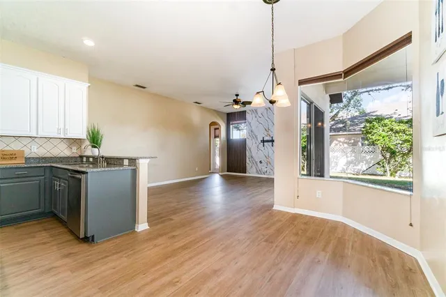 a kitchen with stainless steel appliances granite countertop a refrigerator a sink dishwasher a stove and white countertops with wooden floor