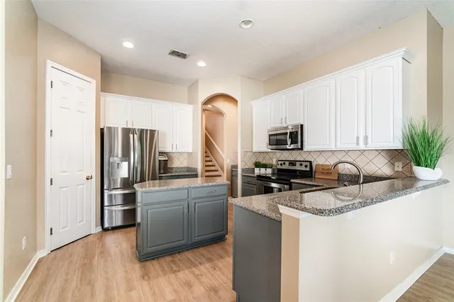 a kitchen with stainless steel appliances granite countertop a refrigerator a stove a sink and a microwave