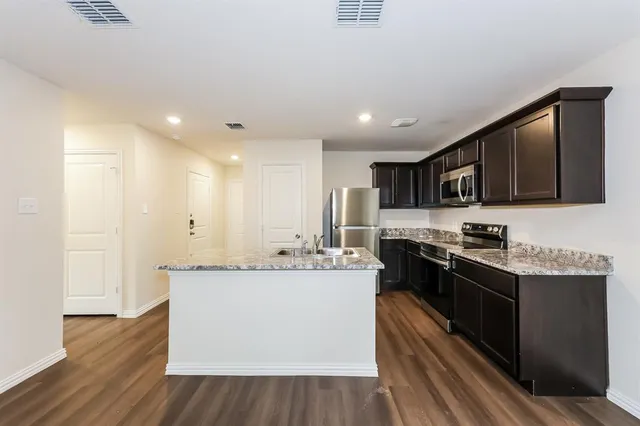 a large kitchen with stainless steel appliances granite countertop a sink stove and refrigerator