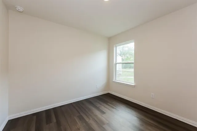 an empty room with wooden floor and window