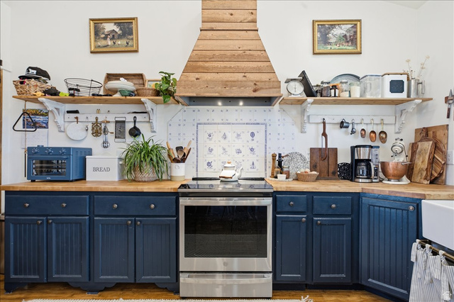 1634 West Arimo Road Arimo, ID 83214 - Photo 8 of 89 Kitchen featuring a stainless steel range, custom wood-finish range hood, blue-and-white patterned backsplash, wood-finish countertops, and blue lower cabinetry