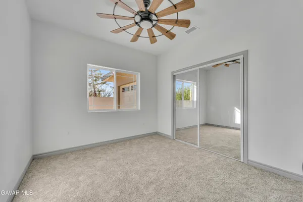 an empty room with chandelier fan and windows