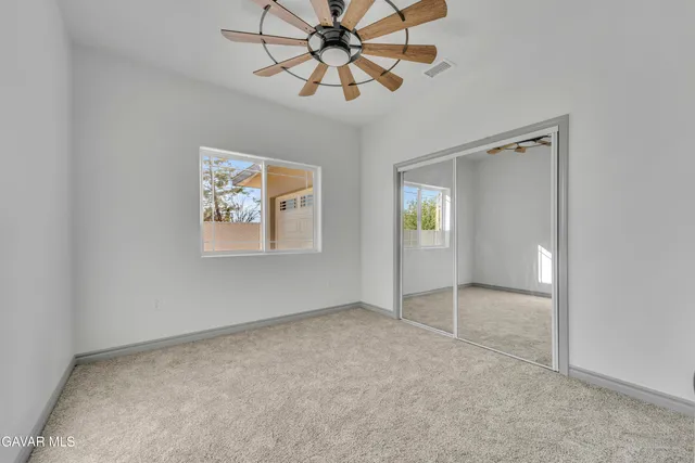 an empty room with chandelier fan and windows