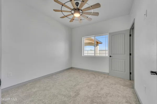 a view of an empty room and chandelier fan