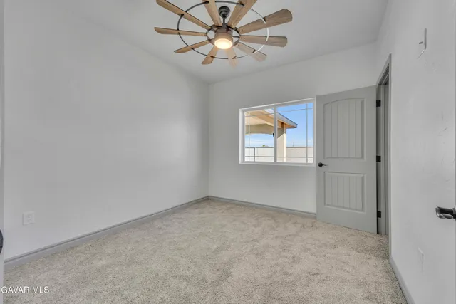 a view of an empty room and chandelier fan