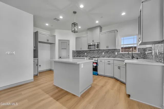 a kitchen with stainless steel appliances kitchen island granite countertop a stove a sink and white cabinets