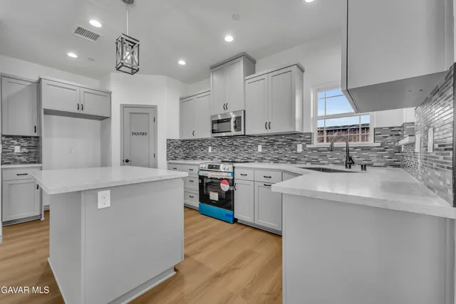 a kitchen with stainless steel appliances granite countertop a sink a stove a refrigerator and a oven