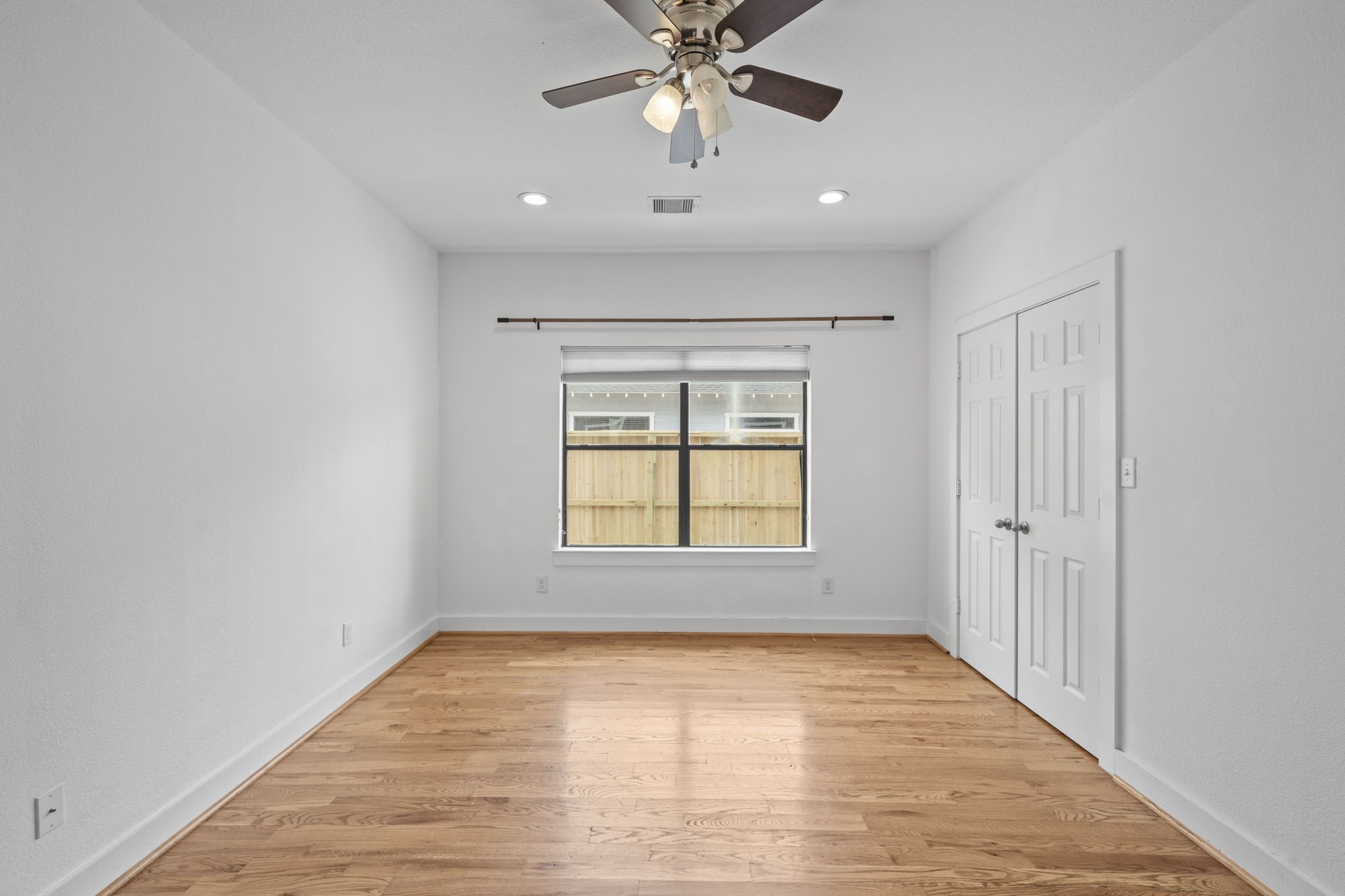 4734 Bell Street, Unit B Houston, TX 77023 - Photo 4 of 10 Living area with warm wood floors, tall ceilings, recessed lighting, and a large front window that keeps the room feeling bright and connected.