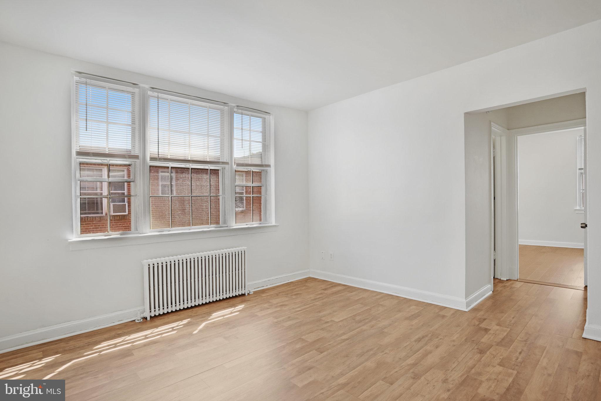 1446 Tuckerman Street Northwest, Unit 306 Washington, DC 20011 - Photo 21 of 26 a view of an empty room with wooden floor and a window