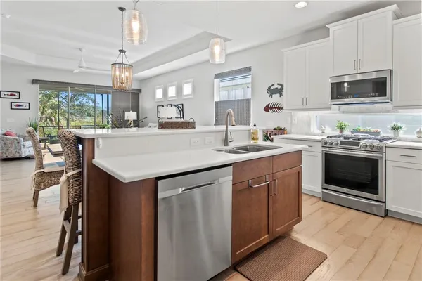 a kitchen with stainless steel appliances granite countertop a refrigerator a sink dishwasher a stove and white cabinets with wooden floor