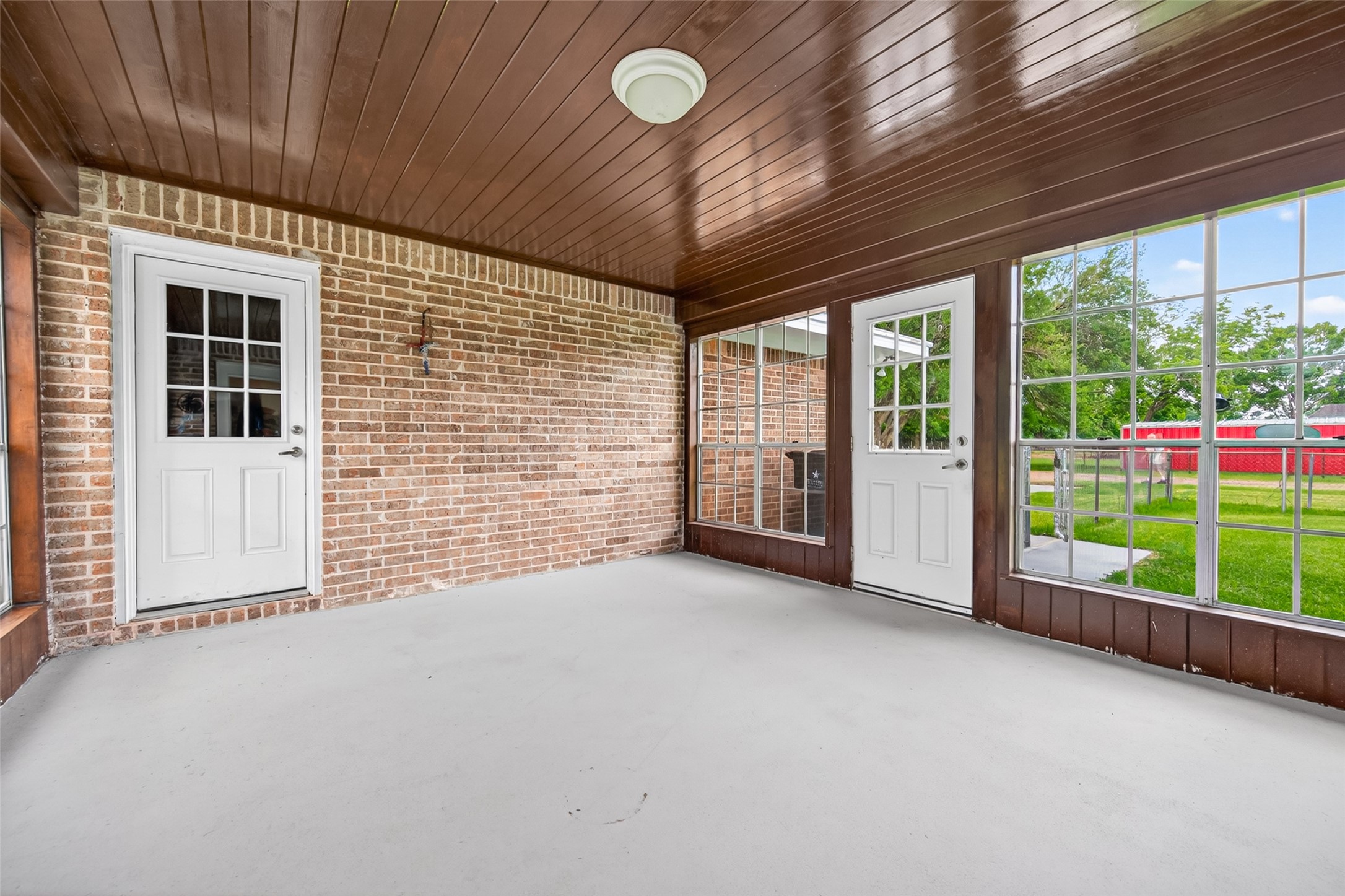 1004 Wagon Road Simonton, TX 77485 - Photo 27 of 40 From this angle, the enclosed back porch truly shines as an extension of the home's living space. Large grid-pane windows wrap the room, flooding it with natural light and offering expansive views of the beautifully maintained backyard.