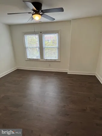 an empty room with wooden floor chandelier fan and windows